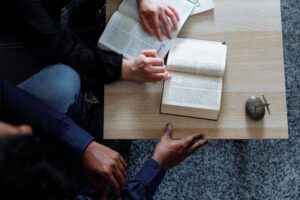Overhead image of two people leaning over a table and reading the Bible together