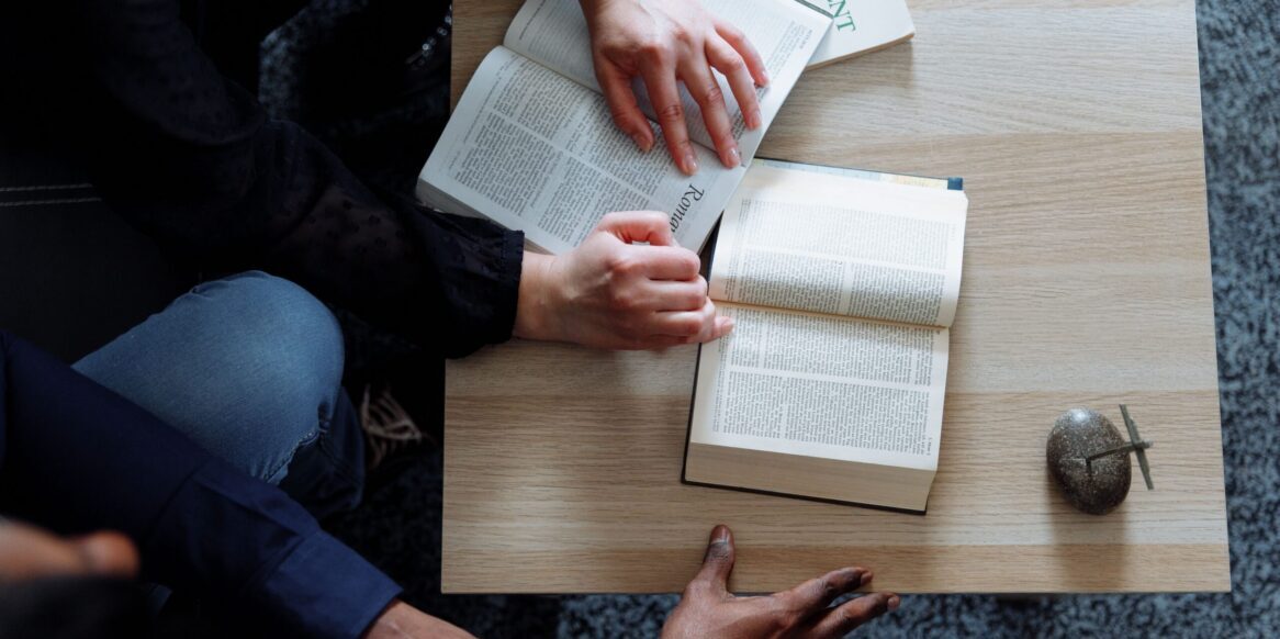 Overhead image of two people leaning over a table and reading the Bible together